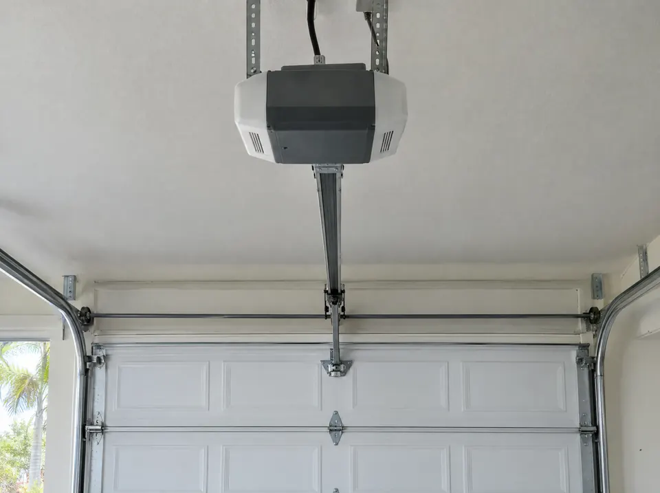 Ceiling-mounted garage door opener with its rail running to a closed white door