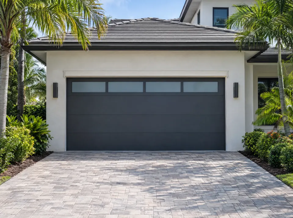 Modern charcoal garage door with frosted windows on a light stucco home